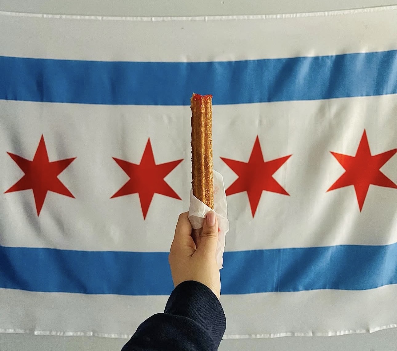 Churro held in front of Chicago flag — Xurro